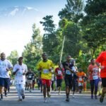 Runners participating in the Kili Marathon with Mount Kilimanjaro in the background. The image captures a vibrant and dynamic scene of the marathon event, showcasing participants in athletic gear, the majestic snow-capped peak of Kilimanjaro, and the scenic landscape of Tanzania. Ideal for highlighting adventure sports, marathon events, and travel experiences in Africa.